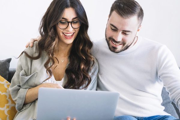 cheerful-couple-with-notebook-on-sofa1