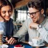 Happy couple watching a movie on smartphone, enjoying resting time at cafe