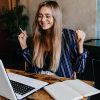 Excited long-haired girl having fun during work with computer. I