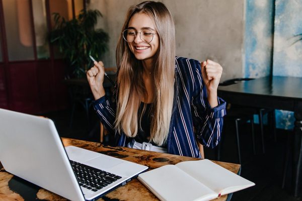 Excited long-haired girl having fun during work with computer. I