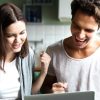 Excited couple ecstatic by online win looking at laptop screen