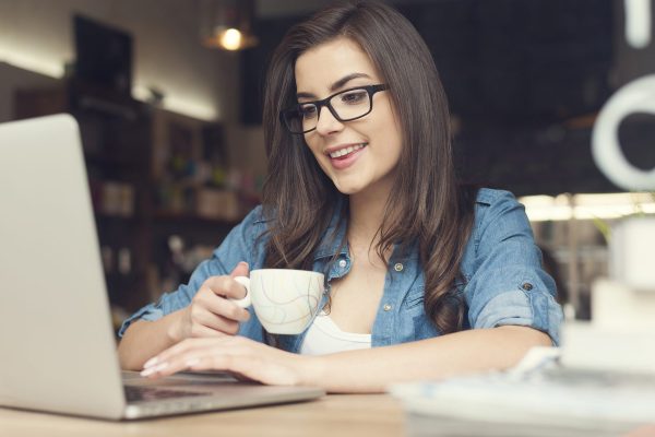 Beautiful hipster woman using laptop at cafe