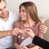 Young smiling couple owners getting keys to own house apartment